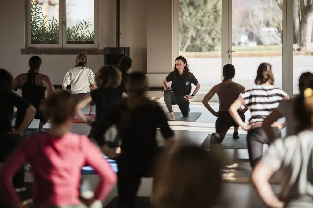 Classe a lezione di yoga in posizione di Anjaneyasana.